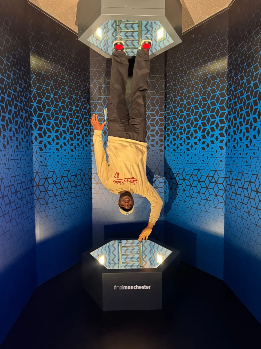 Mayowa in an upside-down illusion room in Manchester
